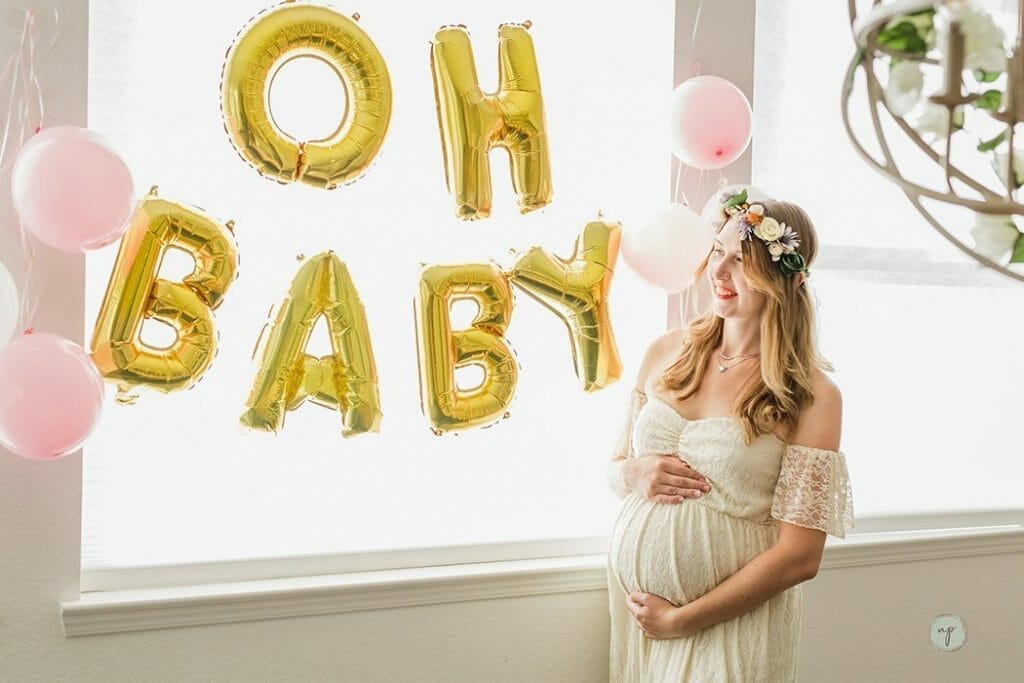 standing next to gold baby balloons